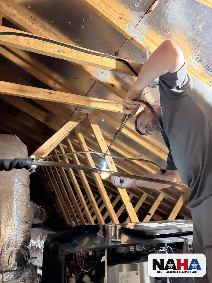 North Alabama Heating and A/C technician brazing a refrigerant line set in a Huntsville attic