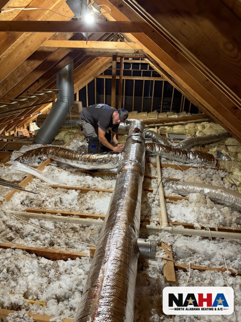 North Alabama Heating & A/C technician connecting a flex duct run to a new insulated trunk line in an attic