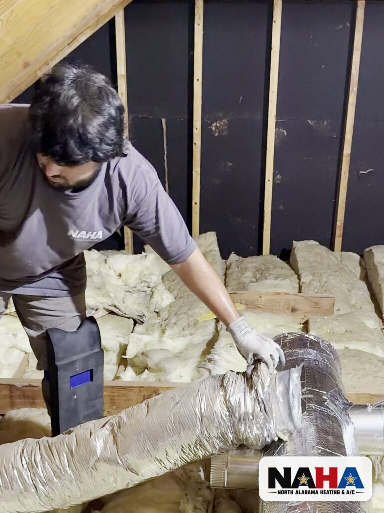 Technician sealing a new flex duct connection in an attic